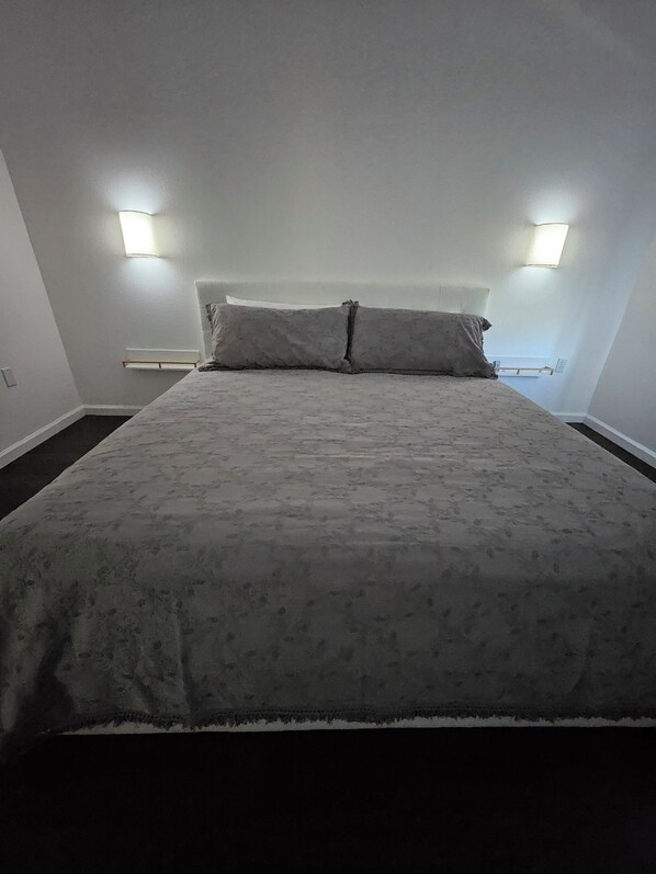 A bedroom with a large bed, two wall-mounted lights, and a window.