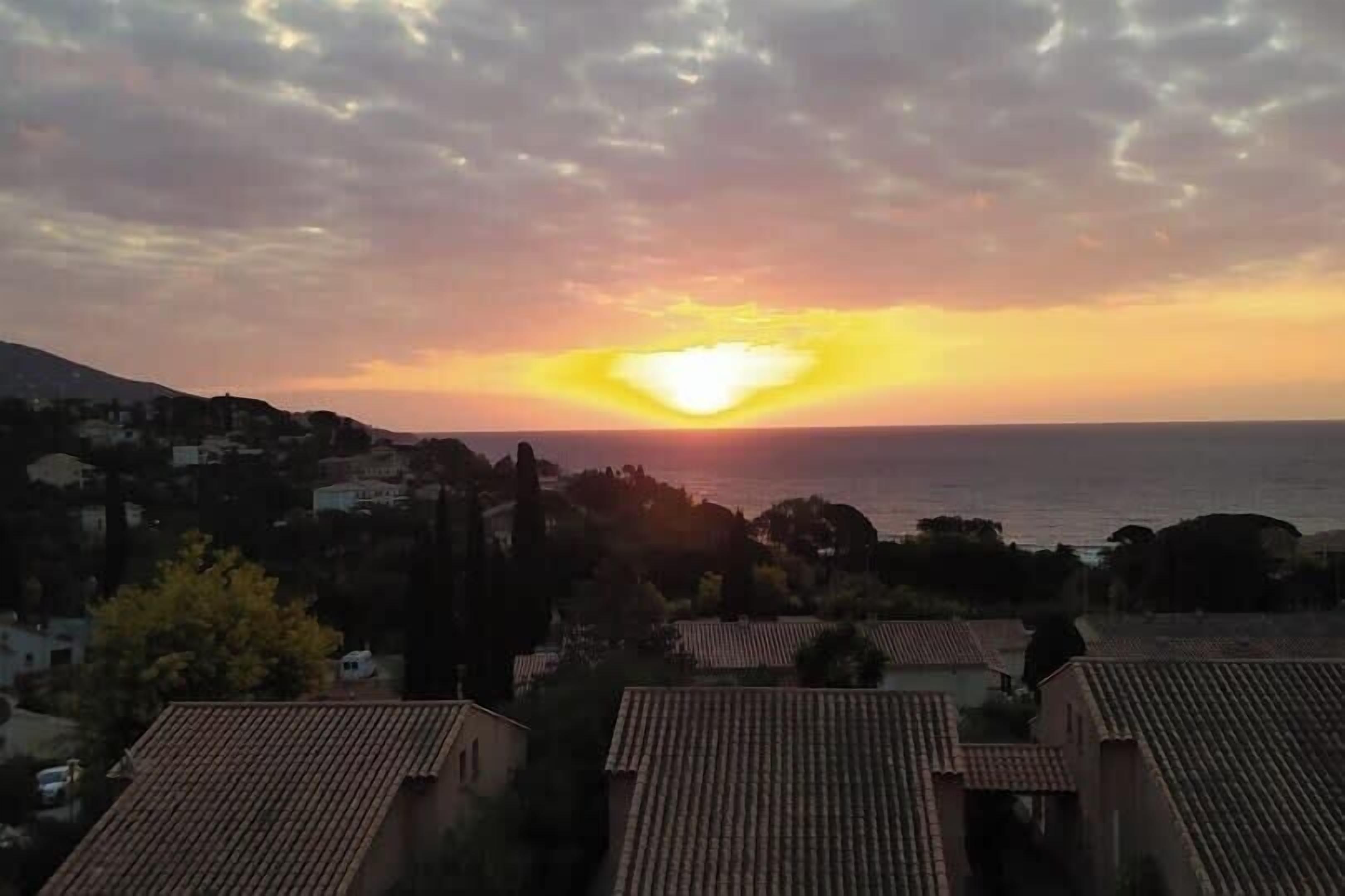 A coastal sunset with buildings in the foreground.