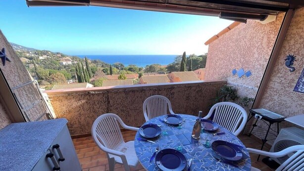 A round table with chairs on a balcony overlooking a coastal view. - Duplex in Pramousquier - sea view (Le Lavandou)