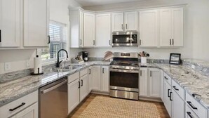 Una cocina moderna con armarios blancos, electrodomésticos de acero inoxidable y encimera de granito.