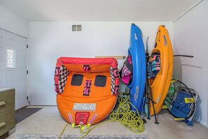 A room with two kayaks, one orange and one blue, and a blue bicycle with a yellow tag.