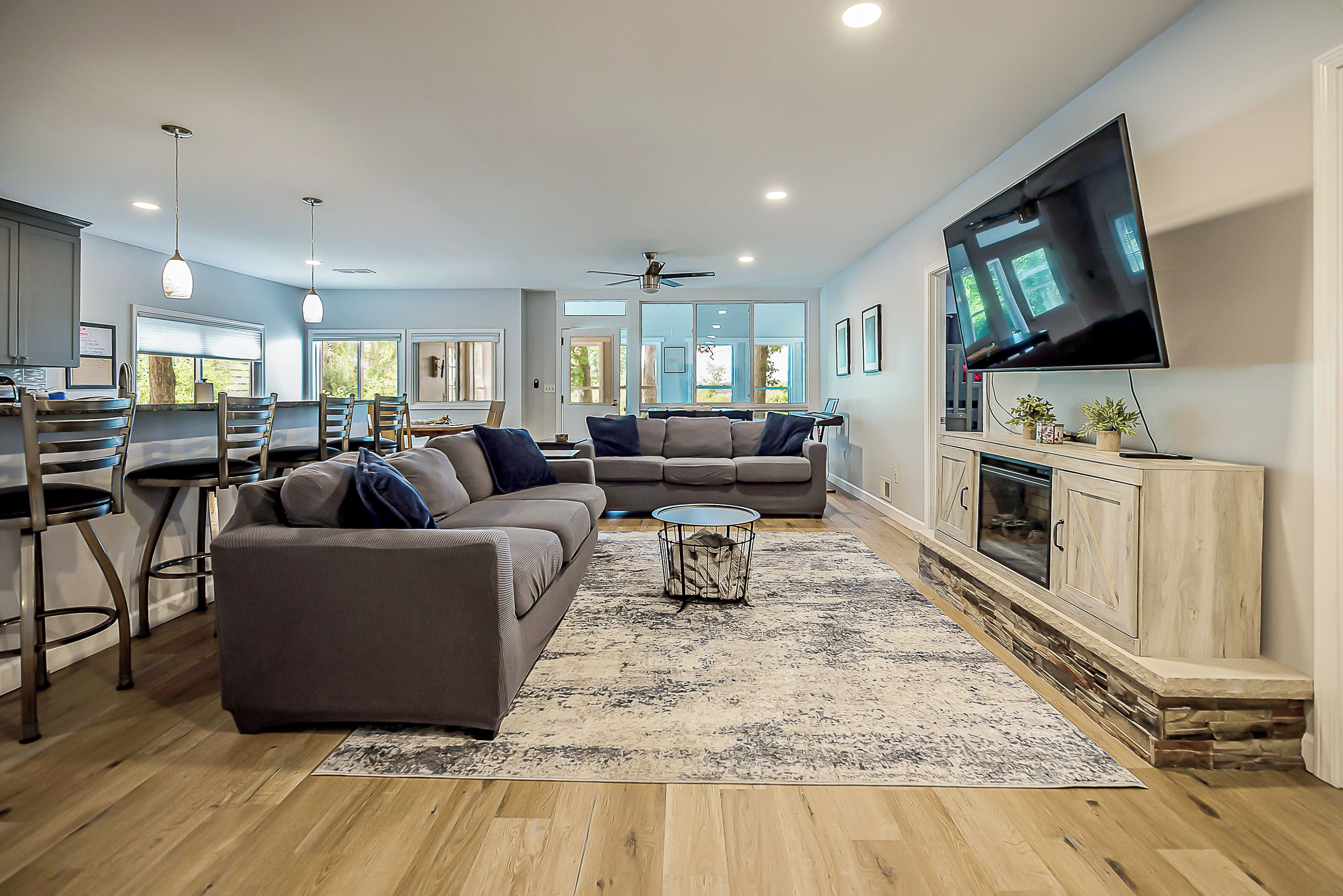 A modern living room with a sofa, a coffee table, and a flat-screen TV mounted on the wall.