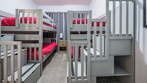 A bunk bed room with a wooden ladder and a nightstand.