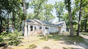 A single-story house with a front porch, surrounded by trees.