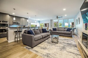 A modern living room with a grey sofa, a coffee table, and a dining area with a bar. - Cozy, quiet cottage on beautiful lake 30 minutes from Ann Arbor (Gregory)
