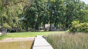 Een houten steiger die uitkomt op een gazon met een huis op de achtergrond.