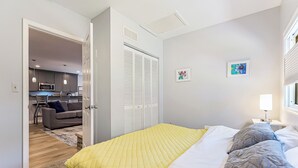 Een slaapkamer met een bed, nachtkastje, lamp en raam.