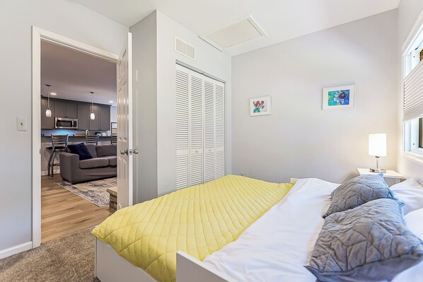 A bedroom with a bed, a bedside table, a lamp, and a window.