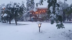 A snow-covered outdoor area with a metal fence and a building in the background. - Idyllic Cottage Memory Making with Pool & Outdoor Fireplace under the Gazebo, (Spokane Valley)