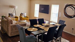 A living room with a sofa, yellow armchair, and a dining table with chairs.