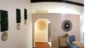 A modern interior with a dining area, a hallway with decorative wall art, and a view into another room.