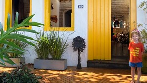 Un edificio con puertas y ventanas amarillas, un camino de ladrillos y plantas en macetas.