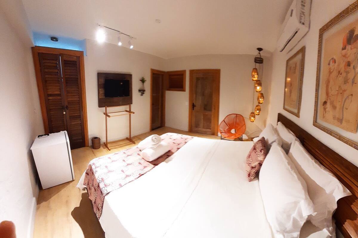 Une chambre d’hôtel avec un lit, une télévision, un petit réfrigérateur et une porte en bois.