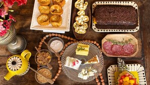 Diversos alimentos, como pasteles, queso y frutas, dispuestos sobre una mesa de madera.