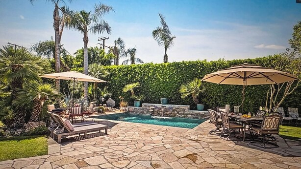 A stone patio with a pool, lounge chairs, and umbrellas. - NEW! Trendy hidden Gem / Private Room with Pool (Palm Desert)