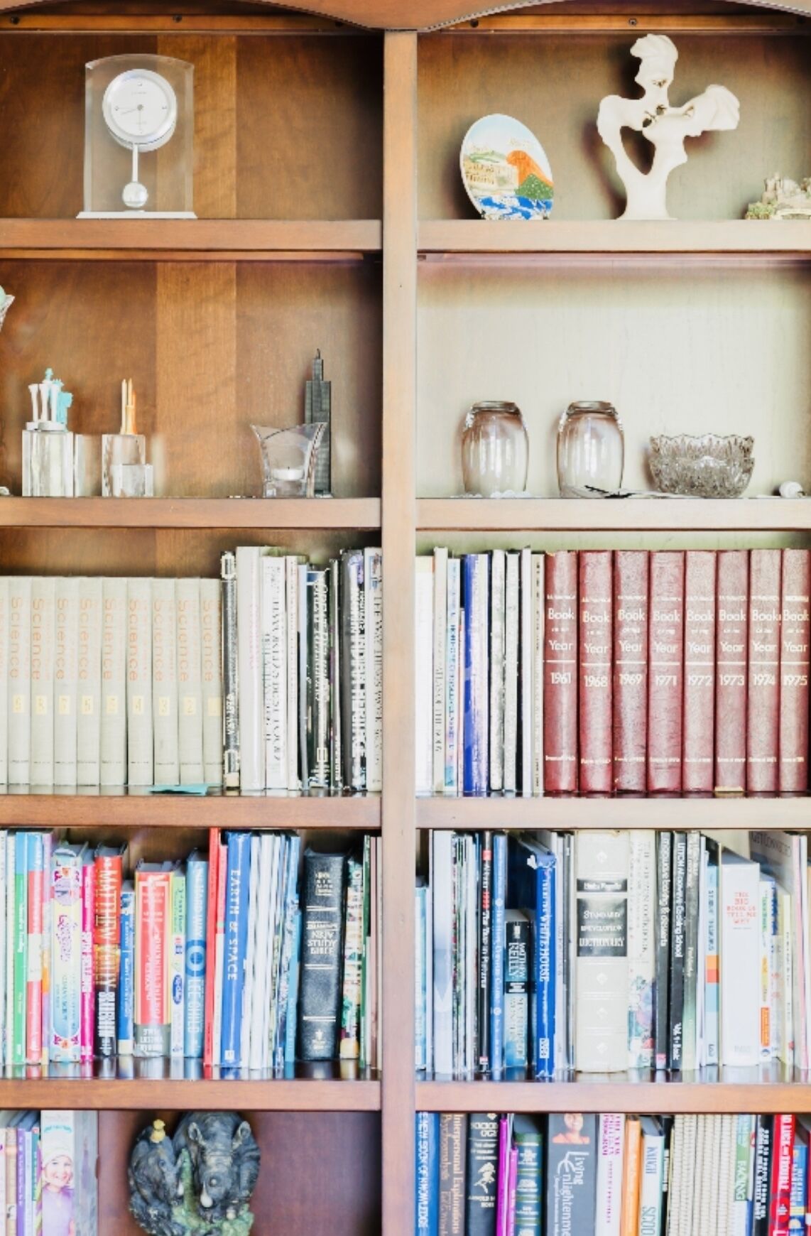 A bookshelf filled with books, decorative items, and a clear glass clock.