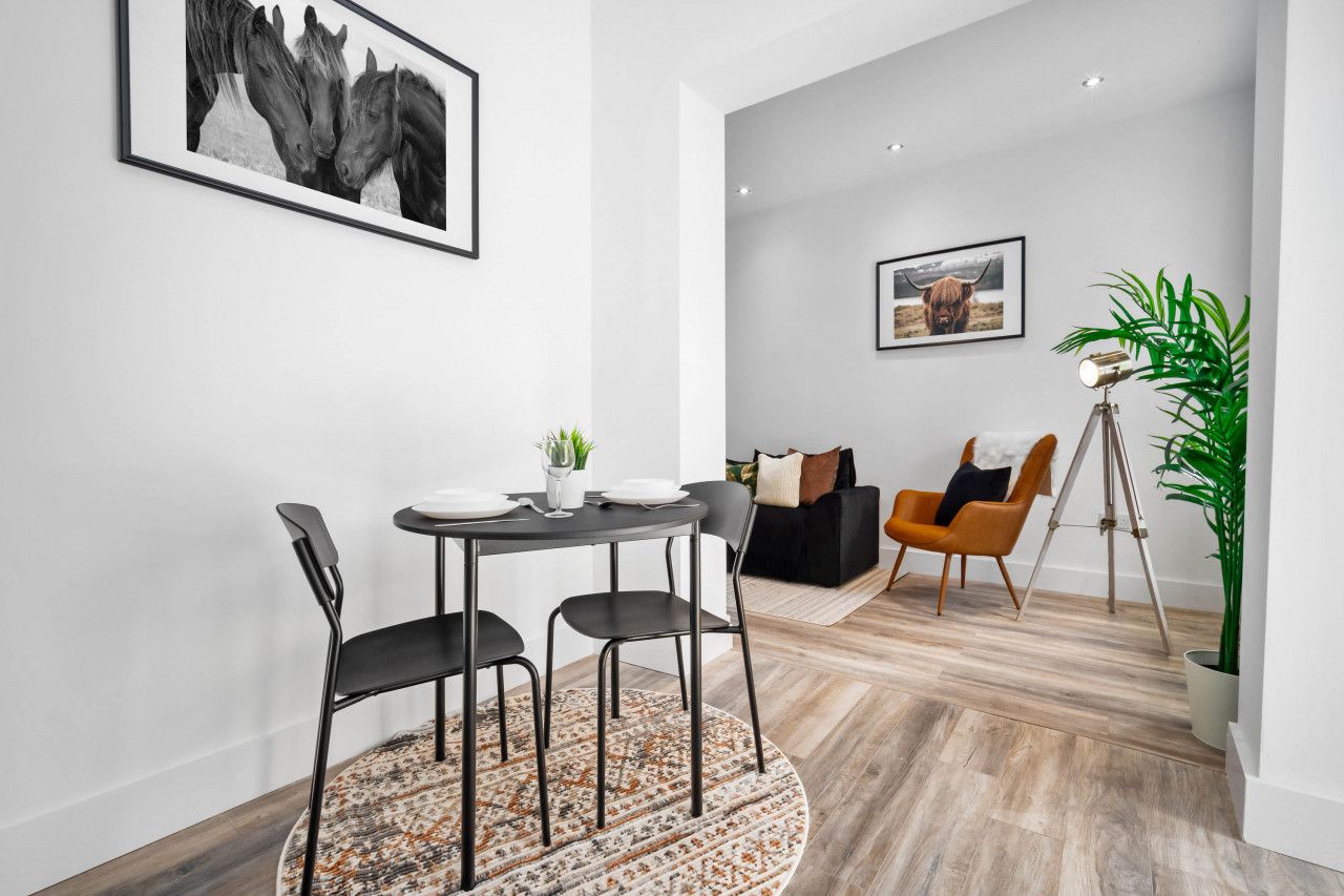 Un espace repas moderne avec une table ronde, des chaises et un tapis.