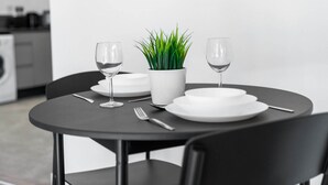 A dining table set with white plates, two wine glasses, a fork, and a potted plant.
