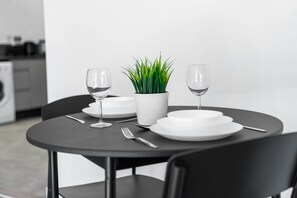A dining table set with white plates, two wine glasses, a fork, and a potted plant.
