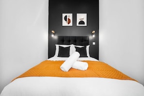 A bed with a black headboard, white bedding, and an orange throw blanket. - Modern Apartment - On Street Parking - Rowley Regis (Halesowen)