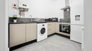 A modern kitchen with a washing machine, microwave, oven, and built-in dishwasher.