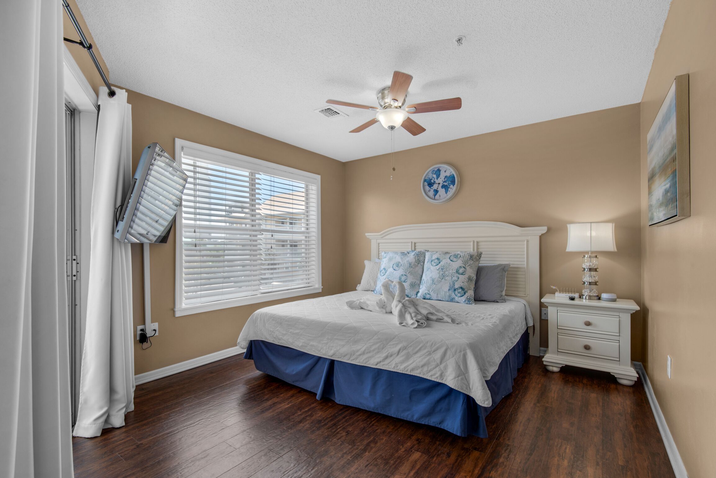 A bedroom with a bed, a ceiling fan, a nightstand, and a window with blinds.