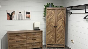 A room with a wooden dresser, a herringbone-patterned wardrobe, and a ceiling light. - Comfy, Clean & Pet Friendly (Gonzales)