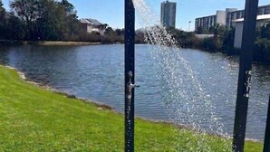 A water feature with a spout, a grassy area, and a body of water.