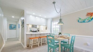 A kitchen with white cabinets, a dining table with chairs, and a hanging light fixture.