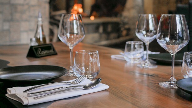 Une table de restaurant mise avec des verres à vin, une bouteille et des couverts.