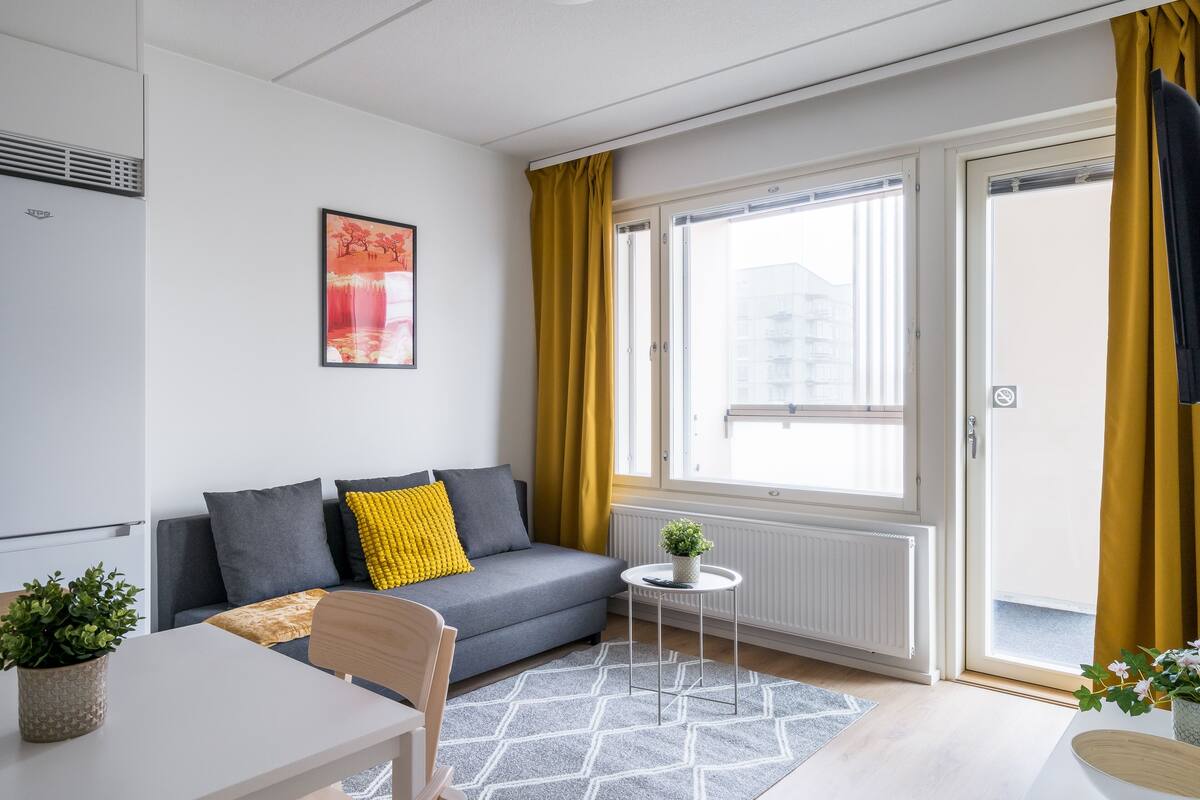 A modern living room with a grey sofa, a small round table, and a potted plant.