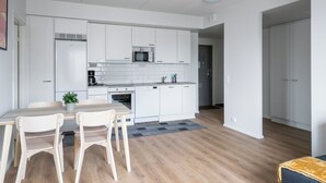 Una cocina moderna con armarios blancos, microondas y un comedor con mesa y sillas.