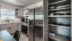 Une cuisine moderne dotée d’appareils électroménagers en acier inoxydable, de meubles blancs et d’étagères intégrées pour le rangement.