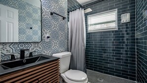 Une salle de bain avec un lavabo noir, des toilettes blanches et un espace douche.