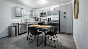 Une cuisine moderne avec des meubles gris, des appareils en acier inoxydable et un îlot central doté de deux chaises.