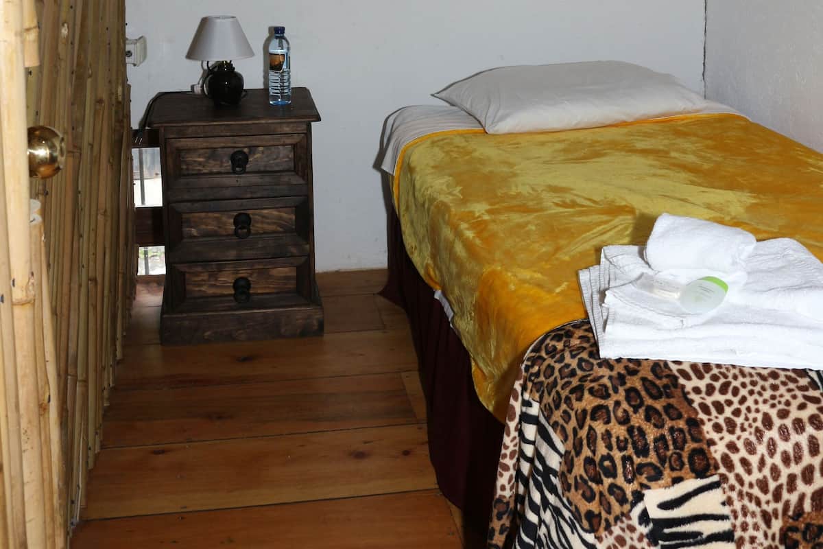 Une chambre avec un lit, une table de chevet et un plancher en bois.
