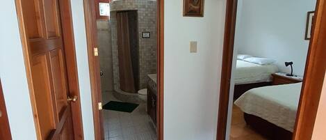 Un pasillo estrecho con puertas de madera que dan a un baño y un dormitorio.