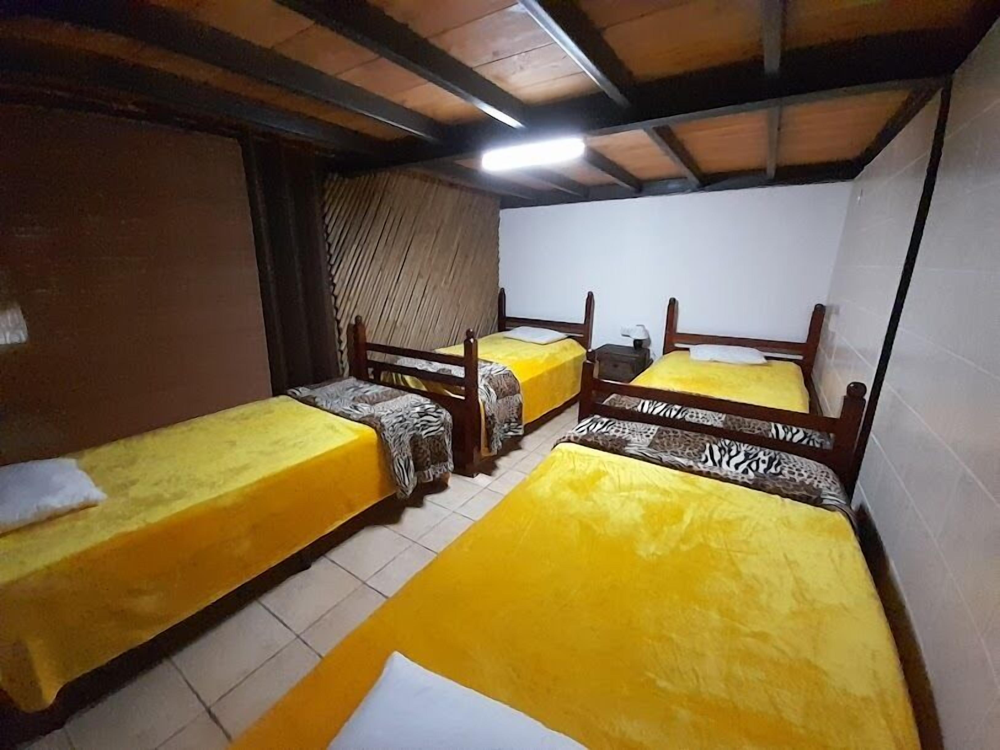 A dormitory room with four single beds, each with a zebra-patterned bedspread.