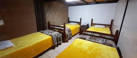 A dormitory room with four single beds, each with a zebra-patterned bedspread.