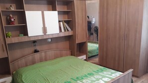 Ein Schlafzimmer mit einem Bett, einem Holzschrank und Regalen mit Büchern und Dekoration.