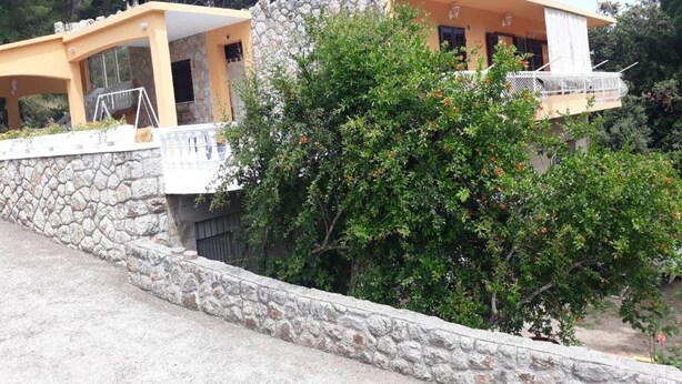 A two-story building with a stone retaining wall and a balcony. - Apartments House Marija - Studio Apartment with Balcony (Vrbanj)