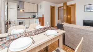 Een kleine leefruimte met een eethoek, kitchenette en een bank.
