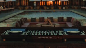 Tocadiscos Pioneer en un área de descanso con vista a la piscina.