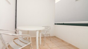 A small, clean room with a white table and two metal chairs, a white sink, and a green-striped countertop. - Studio apartment (Pirovac)