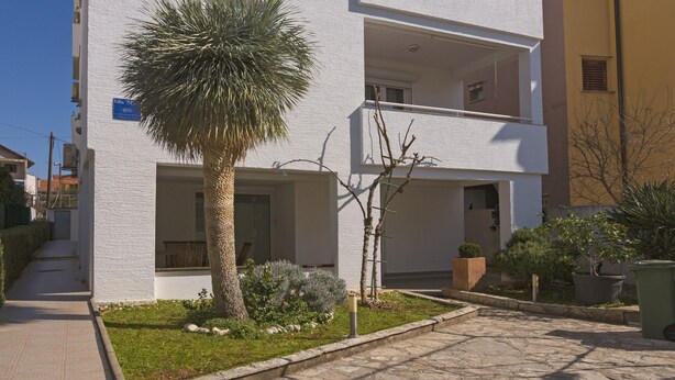 Ein modernes Mehrgeschosshaus mit Balkonen, einer Palme und einem courtyard aus Steinplatten.