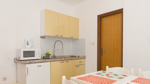 A compact kitchen with a microwave, sink, and cabinets. - Studio apartment on the second floor (Pirovac)
