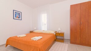A bedroom with a bed, nightstands, a wardrobe, and a framed picture on the wall. - Studio apartment on the second floor (Pirovac)