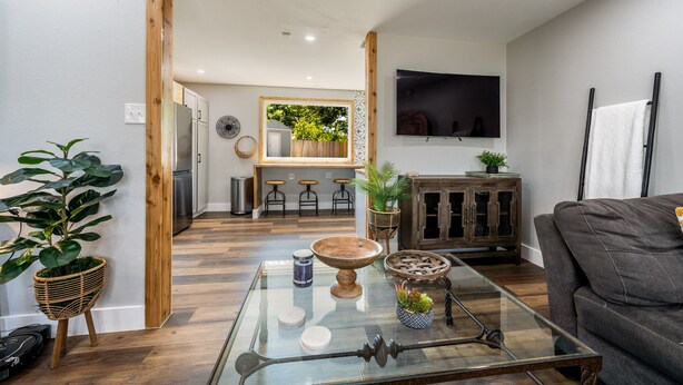 A modern living room with a glass coffee table, wooden floor, and a grey sofa. - Unwind & Recharge in Style! Honey Bee Cottage is a Perfect Medical Ctr. Retreat! (San Antonio)