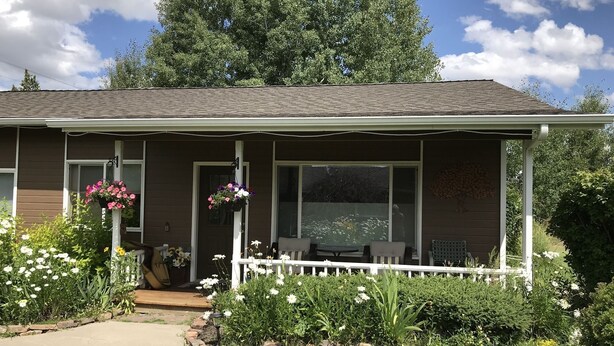 A two-story house with a porch, a small garden, and a pathway leading to the entrance.