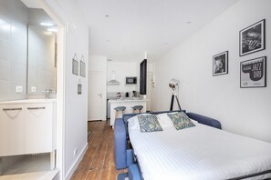 Cozy retreat with a neatly made bed, compact kitchenette, and desk area.